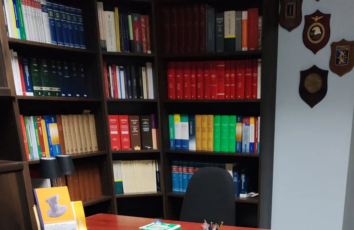 La stanza dello studio con la libreria dei codici, la scrivania e le sedie per i clienti